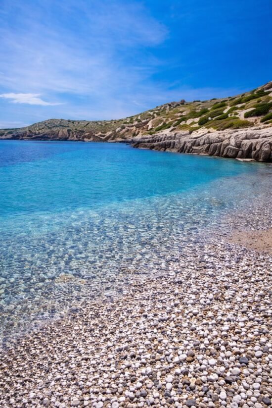 Turquoise waters and pebble shoreline at Karfas Beach in Chios, Greece
